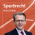 Beitragsteaser des Newsbeitrages zum Sportrecht. Zu sehen ist eine Rennbahn auf orangenem Grund. Im Vordergrund befindet sich der Autor Henner Hentsch.